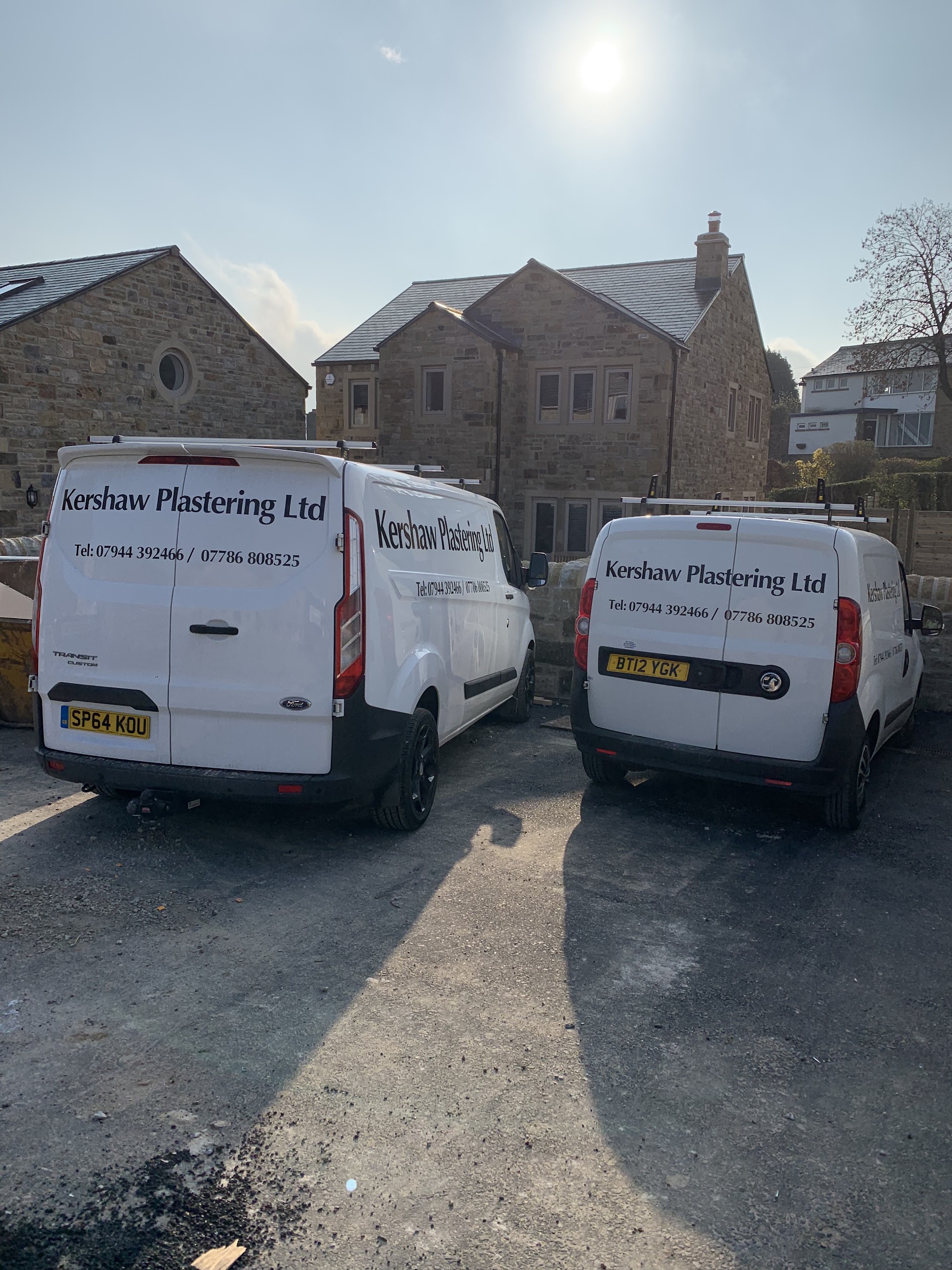 Two white vans carrying the Kershaw Plastering Ltd name and telephone number